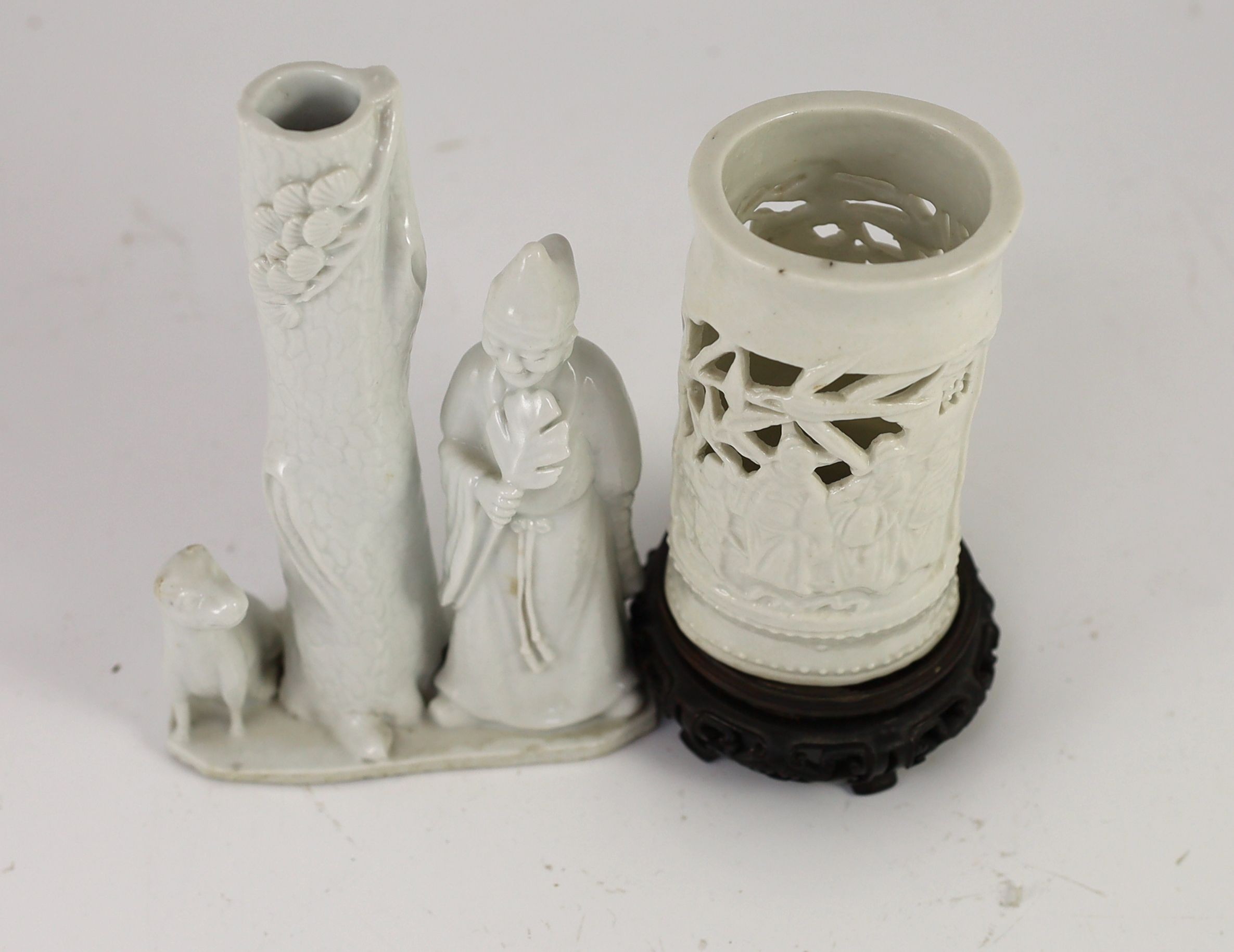 A Chinese blanc-de-chine figural joss stick holder and a similar brushpot, Dehua kilns, 18th/19th century, 16cm high & 11cm plus wood stand